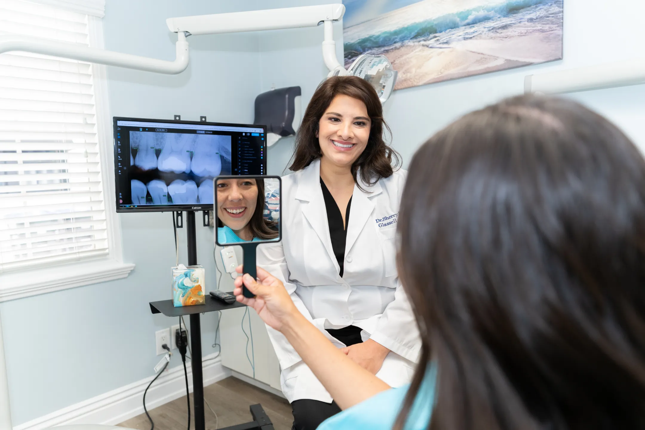 Patient checking her new smile in a hand mirror with Dr. Sherry Darabi